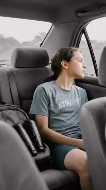 Joven deportista viajando en el asiento trasero de un coche durante el trayecto de vuelta, Papás Uber